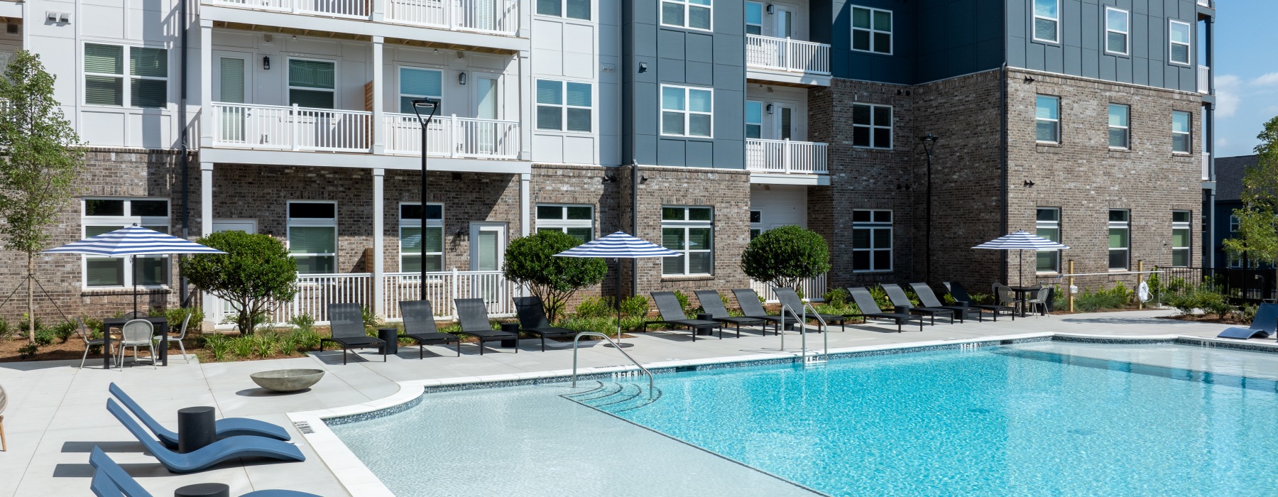 a swimming pool with chairs and umbrellas next to it