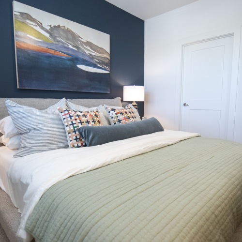 Relax and recharge in beautiful and spacious bedrooms Large bed with painting on wall at The Laurel apartments in Flowery Branch, GA.