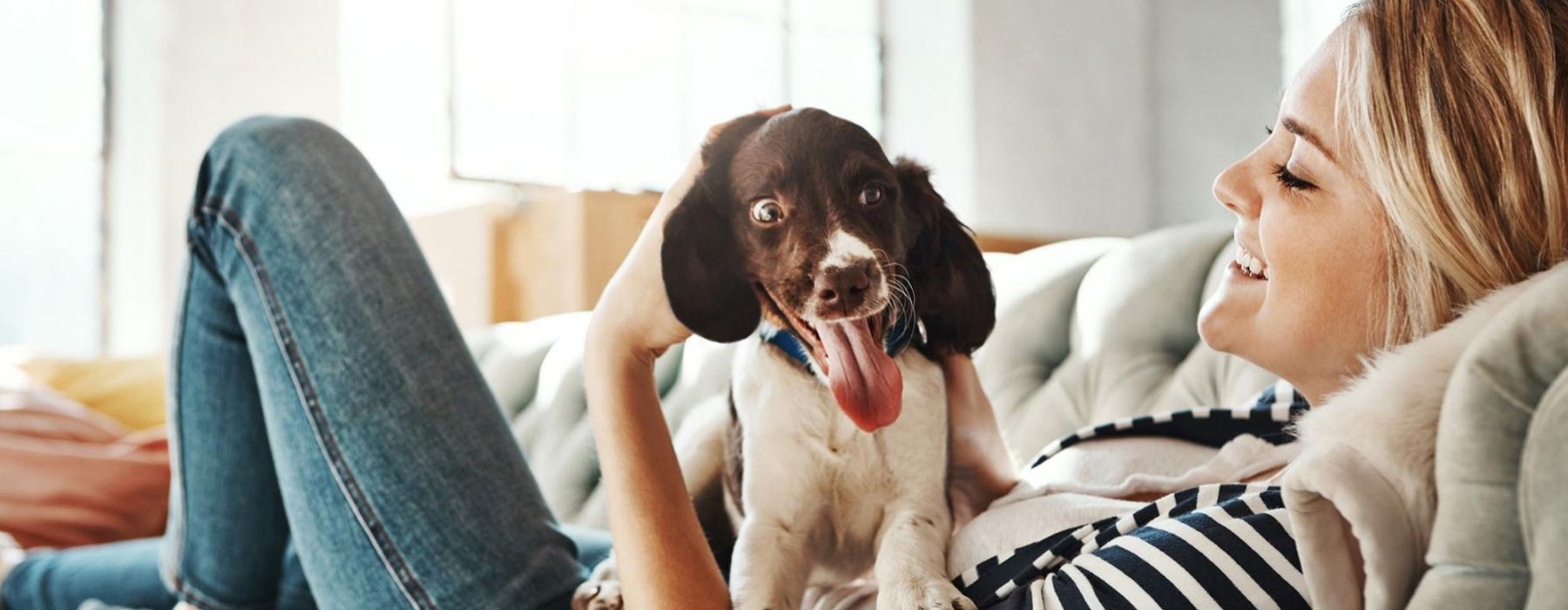 woman lies on a couch and pets her dog