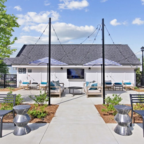 benches and additional seating, an outdoor tv, umbrellas, and string lights benches and additional seating, an outdoor tv, umbrellas, and string lights